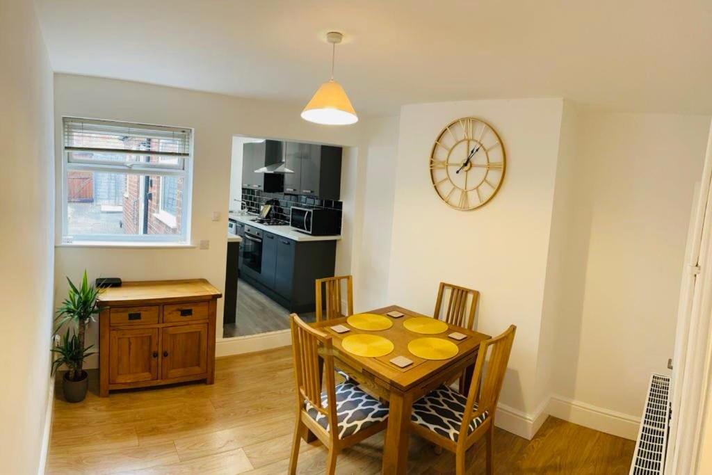 a dining room with a table and chairs and a clock at Stylish cottage - Parking for 2 cars! in Lincolnshire