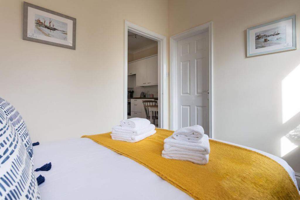 a room with a bed with towels on a yellow blanket at Promenade Apartments Maldon in Maldon