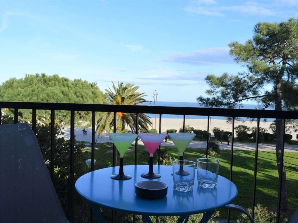 een blauwe tafel met wijnglazen op een balkon bij Appartement Argelès-sur-Mer, 2 pièces, 4 personnes - FR-1-225-696 in Argelès-sur-Mer