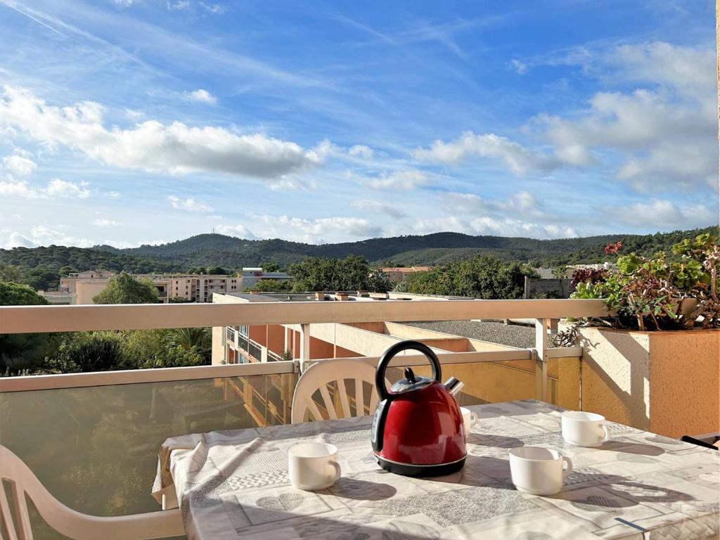 une bouilloire pour thé rouge assise sur une table sur un balcon dans l'établissement Appartement 2 pièces, 4/5 couchages, proche plage et commodités, parking inclus, Bormes-les-Mimosas - FR-1-251-432, à Bormes-les-Mimosas