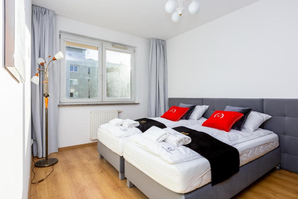 a bedroom with a large bed with red pillows at ApartamentyGdansk EU Marina Primore in Gdańsk