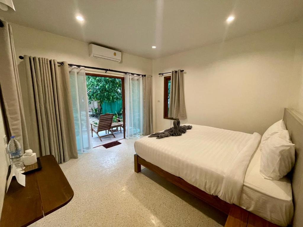 Schlafzimmer mit einem Bett, einem Tisch und einem Fenster in der Unterkunft Sunny Cove Beach Resort Koh Phayam in Ranong