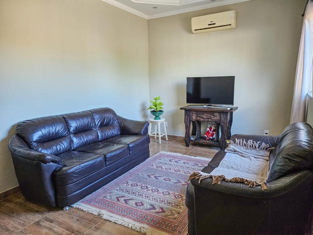 a living room with a leather couch and a television at Casa confortável em Brotas in Brotas
