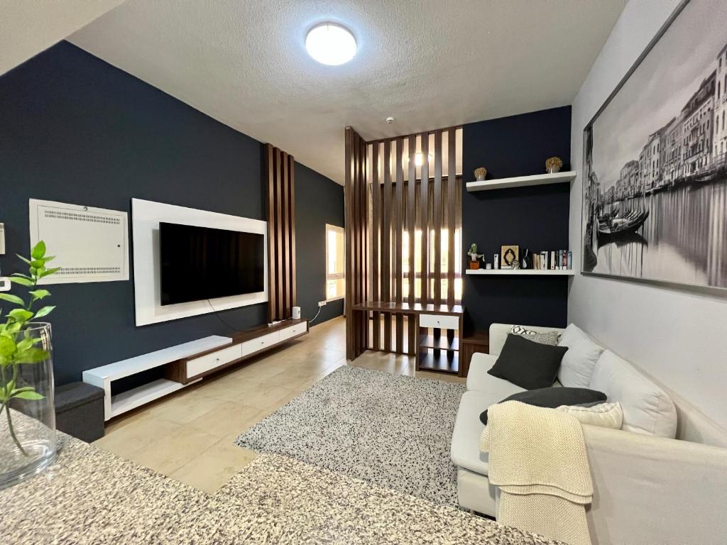 uma sala de estar com um sofá branco e uma televisão em Entire apartment in Remraam community em Dubai