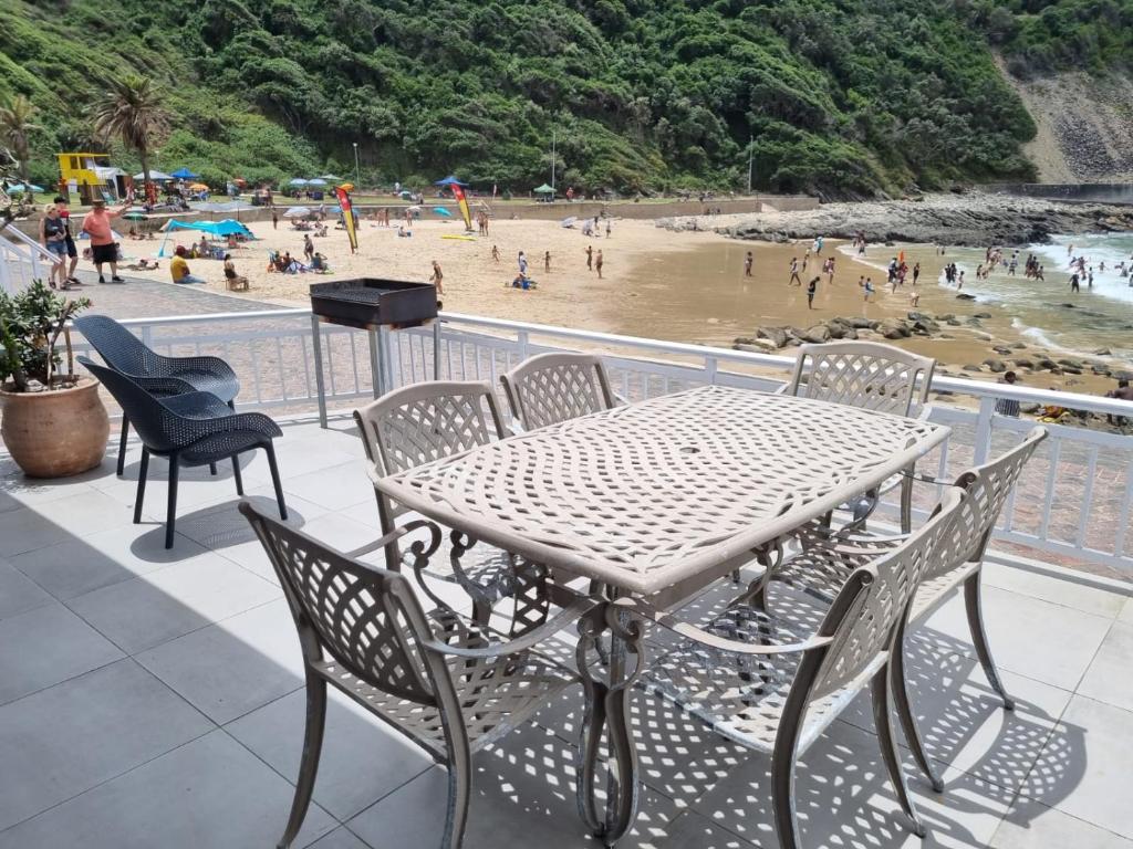 a table and chairs on a balcony overlooking a beach at Beachfront property, Victoria Bay, Garden route in Victoria Bay