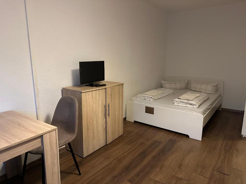 Cette petite chambre comprend un lit avec un bureau et une chaise. dans l'établissement Gepflegte Wohnungen in der Innenstadt, à Dortmund