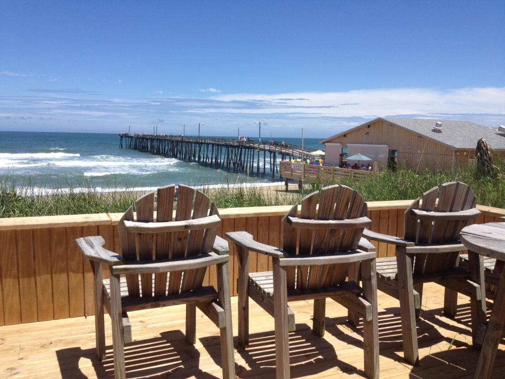 a deck with four chairs and a table and a pier at Colonial Inn in Nags Head