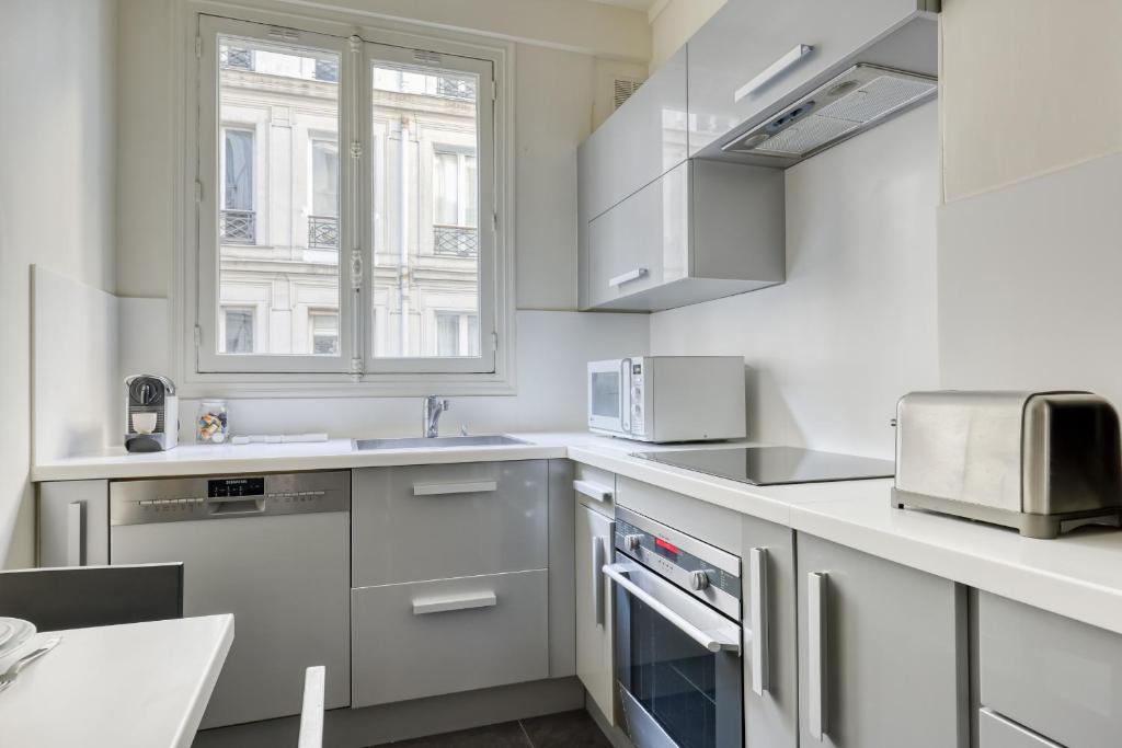 a kitchen with white appliances and a window at Gorgeous and large flat in the heart of Paris 09 in Paris