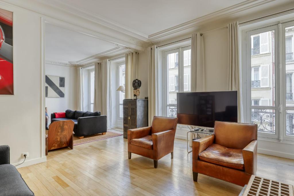 a living room with chairs and a flat screen tv at Gorgeous and large flat in the heart of Paris 09 in Paris