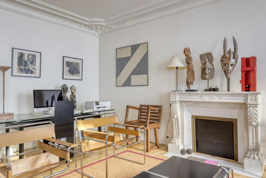a living room with a fireplace and a desk and chairs at Gorgeous and large flat in the heart of Paris 09 in Paris