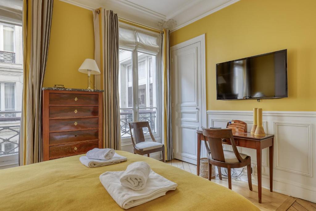 a bedroom with a bed and a desk and a tv at Gorgeous and large flat in the heart of Paris 09 in Paris