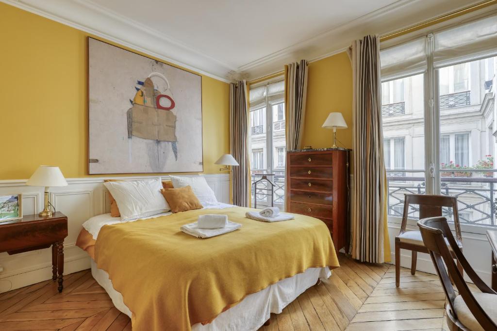 a bedroom with a bed with yellow walls and windows at Gorgeous and large flat in the heart of Paris 09 in Paris