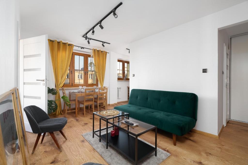 een woonkamer met een groene bank en een tafel bij Comfortable Two-Bedroom Apartment Poznań by Renters in Poznań