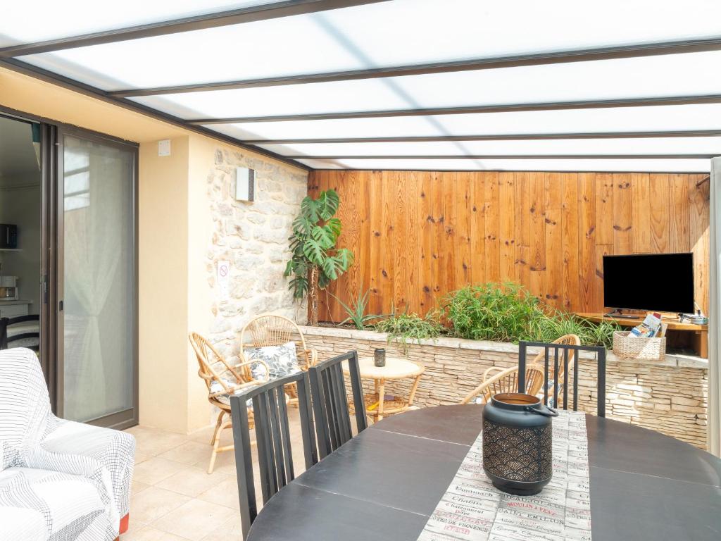 une terrasse avec une table, des chaises et une télévision dans l'établissement Appartement Soleil levant 4 à 5 Personnes, à Millau