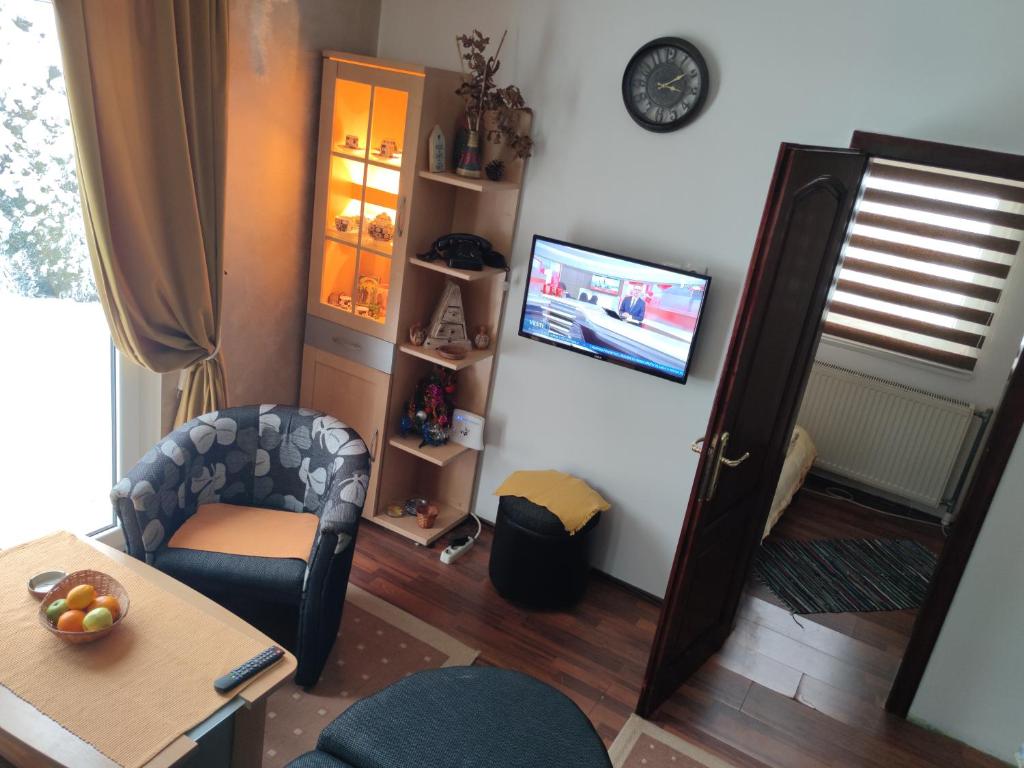 ein Wohnzimmer mit einem Tisch, einem Stuhl und einem TV in der Unterkunft Apartment Ilic in Zlatibor