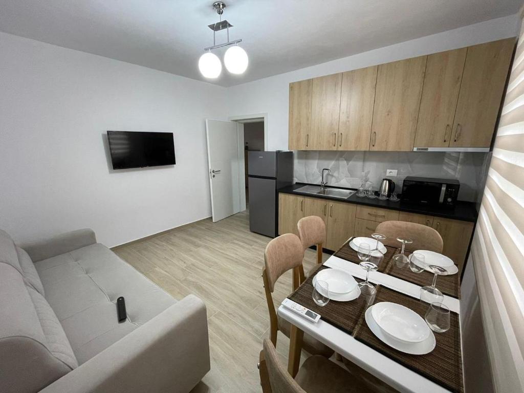 ein Wohnzimmer und eine Küche mit einem Tisch und einem Sofa in der Unterkunft Kevi ‘s place in Tirana