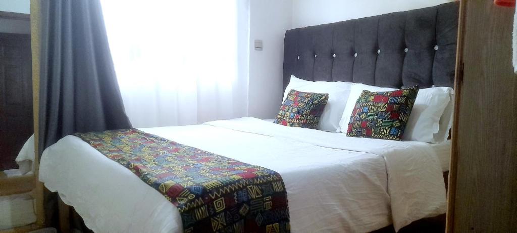 sypialnia z dużym białym łóżkiem z czarnym zagłówkiem w obiekcie faraja homes w mieście Kakamega