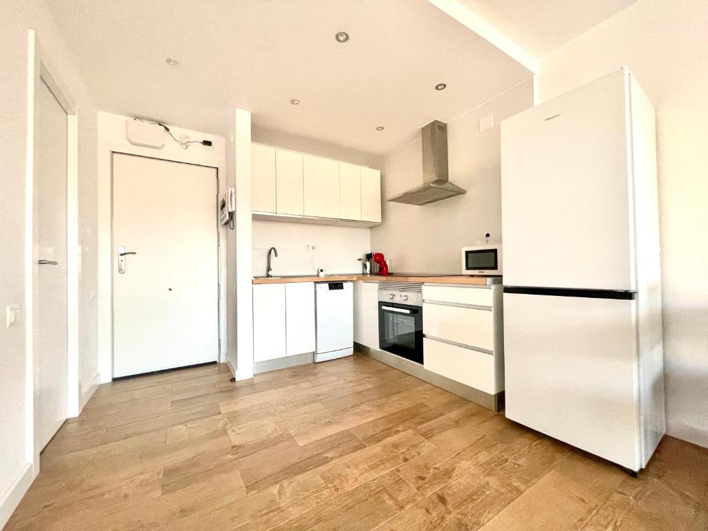 uma cozinha com armários brancos e piso em madeira em Costa Daurada Apartaments - AQUARIO PINEDA em La Pineda