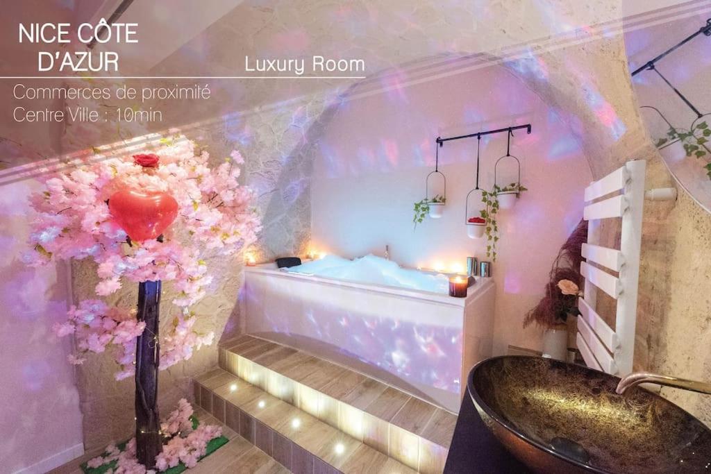 La salle de bains est pourvue d'une baignoire, d'un lavabo et de fleurs. dans l'établissement Love Room avec 2 Jacuzzi Balnéo, Parking, à Nice