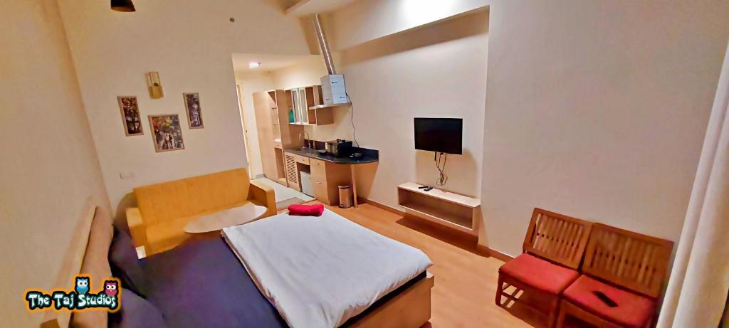 a small room with a bed and a television at Taj Suites & Studios-Top Place Couple Friendly Stay at Luxury Gaur City Mall #Movie, #Food Court #Shopping in Ghaziabad