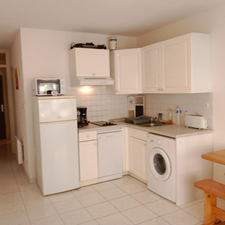 une cuisine avec des armoires blanches et une laveuse et une sécheuse dans l'établissement Studio cabine équipée pour 4 personnes 4CALYI/2, à Canet