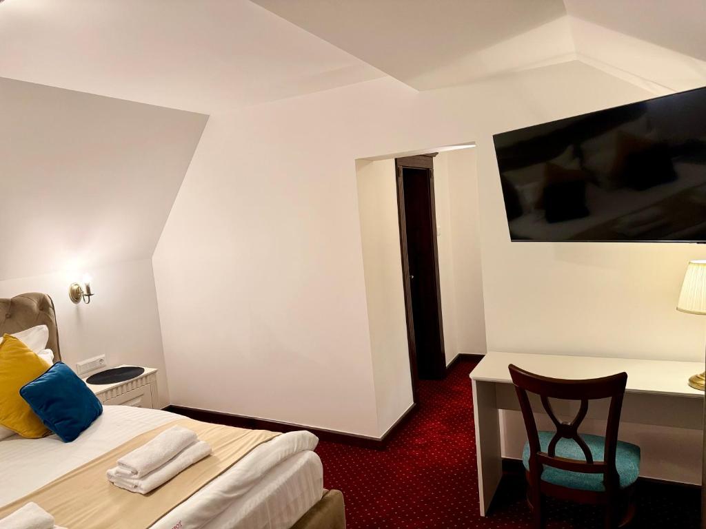 シナイアにあるVila Șipot - Casa Arhitecțilorのベッド、デスク、椅子が備わるホテルルームです。
