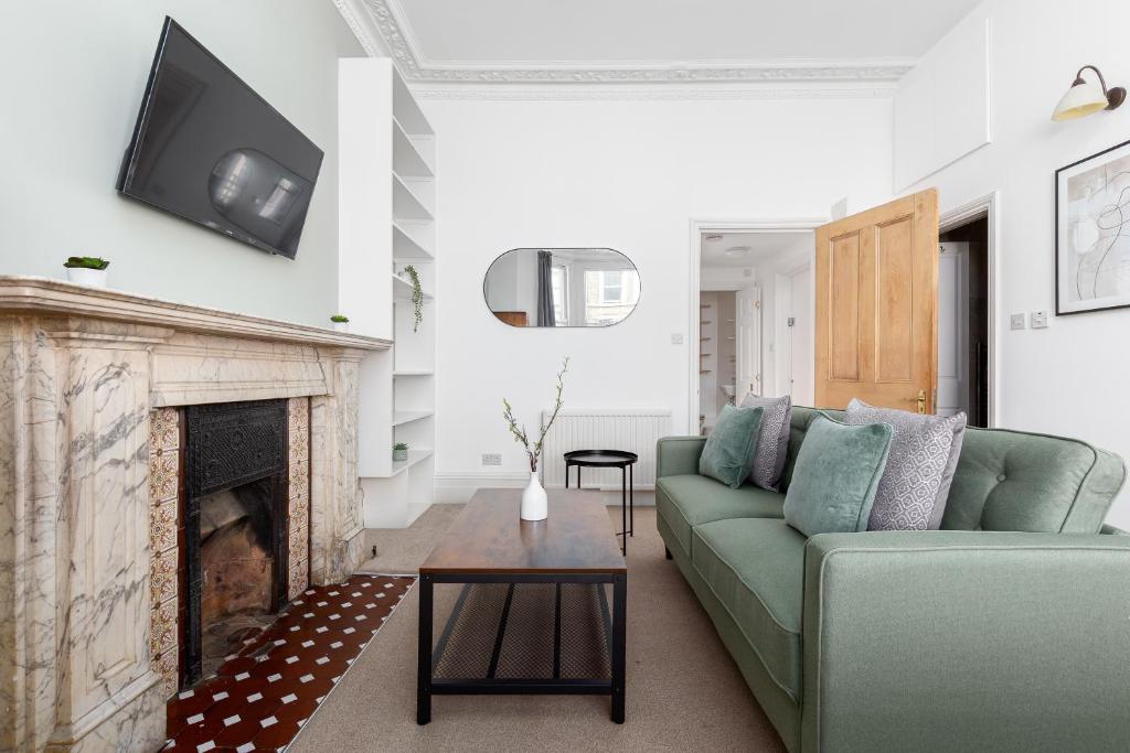 een woonkamer met een groene bank en een open haard bij The Kensington Apartments in Londen