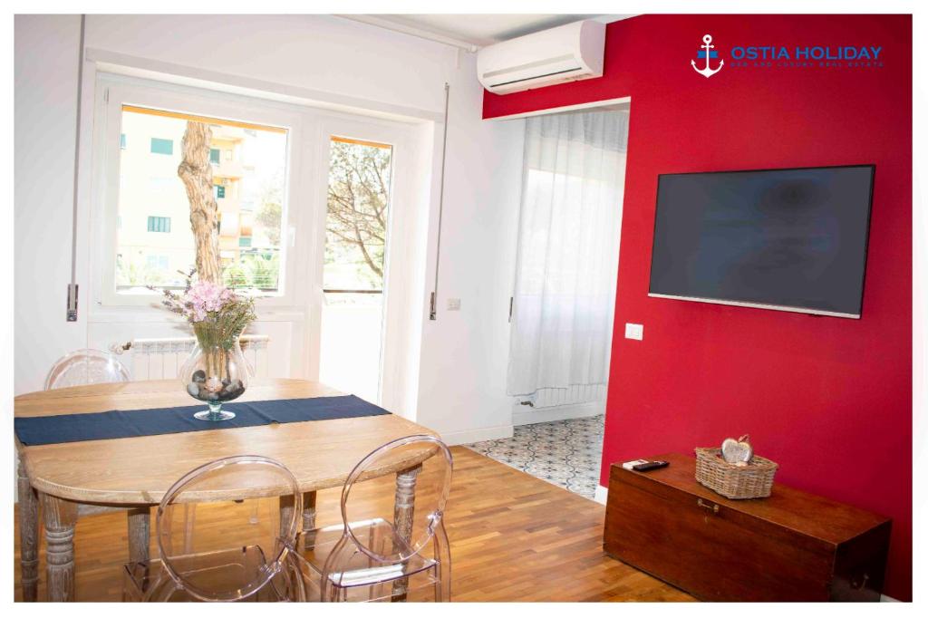 a dining room with a table and a red wall at Appartamento Executive Home in Lido di Ostia