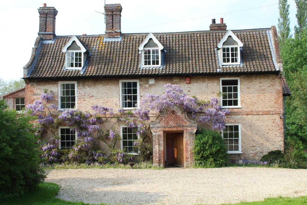 an old brick house with a wreath of purple flowers on it at Beautiful 18th Century Old Rectory with river in Norwich