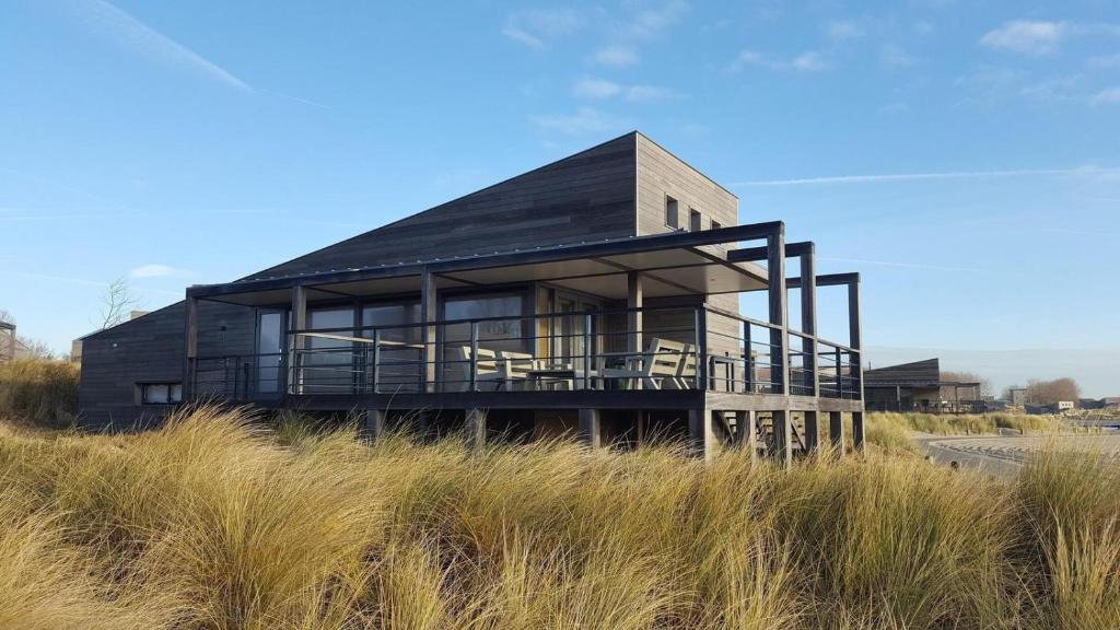 a house sitting on top of a hill at Luxury Beachfront Villa 4p - Uitzicht op de Baai & Duinen - Villa 19 in Ouddorp