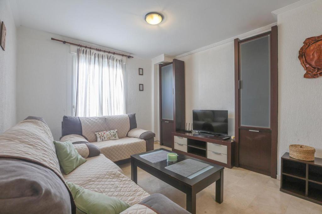 uma sala de estar com um sofá e uma televisão em Santa María 13 em Huelva