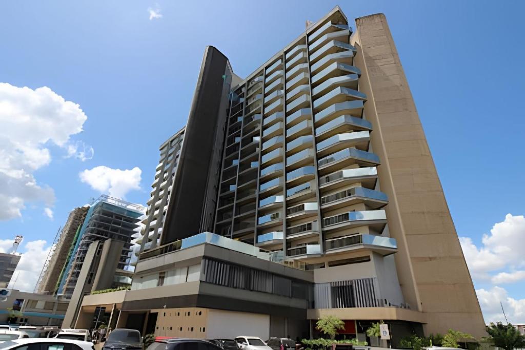 a tall building with cars parked in a parking lot at Ozped Private Flats Manhatan in Brasília