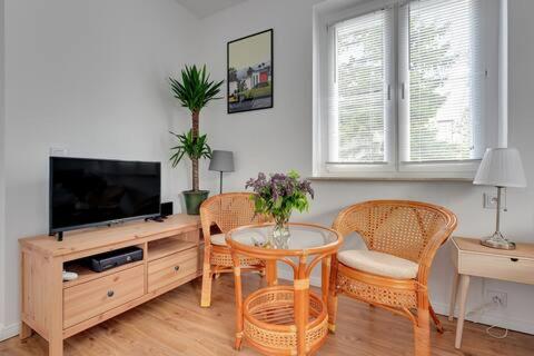 een woonkamer met een tv en een tafel en stoelen bij Pegaz 1 in Sopot