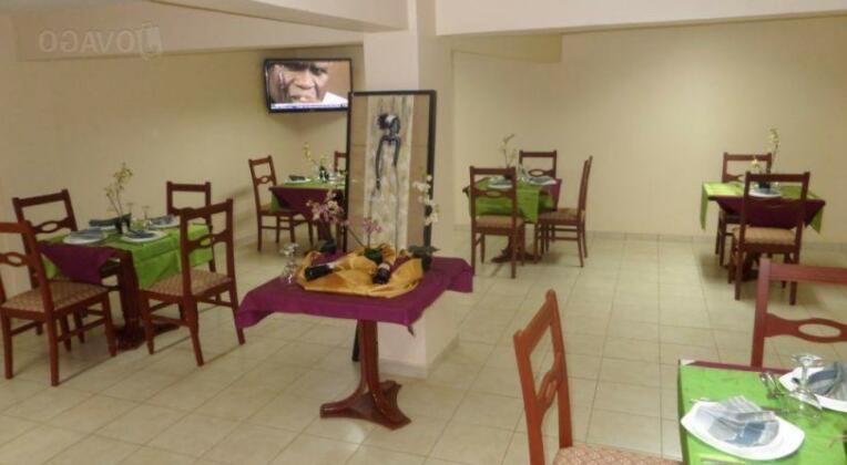 ein Esszimmer mit Tischen und Stühlen sowie einem TV in der Unterkunft MAKO PALACE Hôtel in Bafoussam