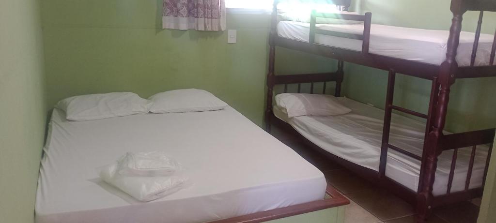 two bunk beds in a room with white sheets at Agencia e Pousada - Capitolio - MG in Capitólio