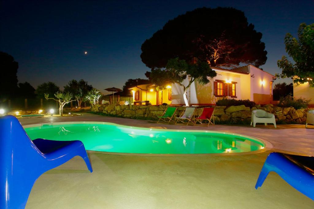 una piscina notturna con una casa sullo sfondo di Villa 2 Pini ad Alcamo