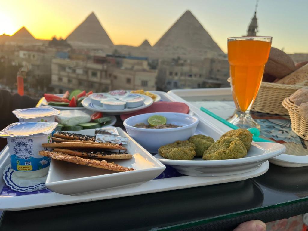 een dienblad met eten op een tafel met een drankje bij Loca Pyramids View in Caïro