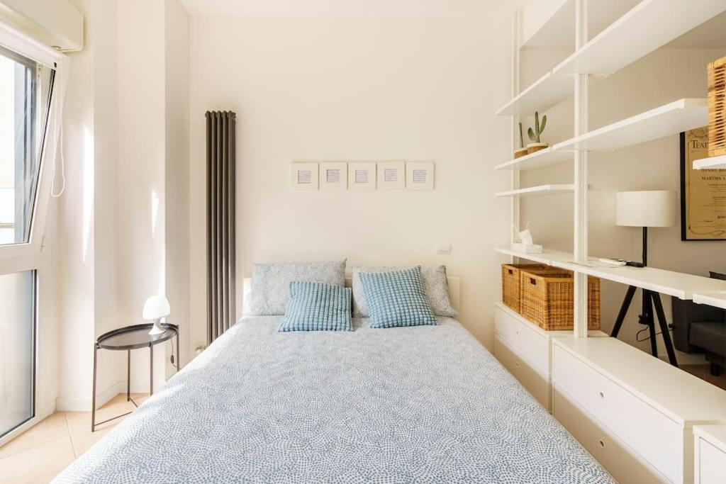 Dormitorio blanco con cama con almohadas azules en Brand new large studio with parking - Opera studio en Milán