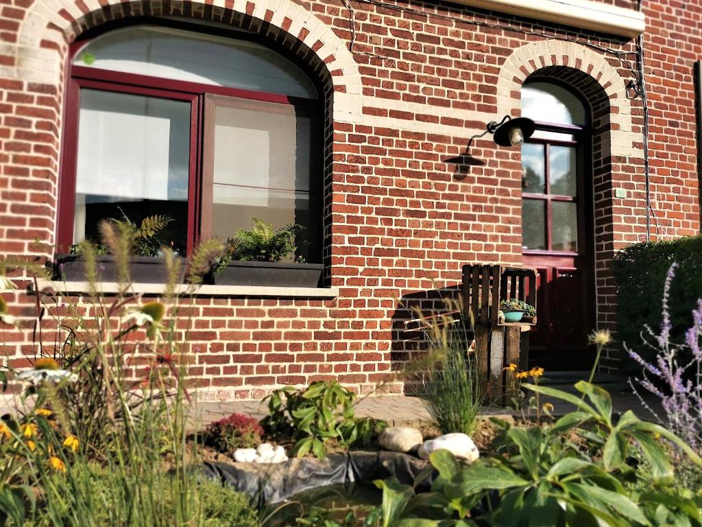 een bakstenen gebouw met een raam met planten erin bij At Huis in Boeschèpe