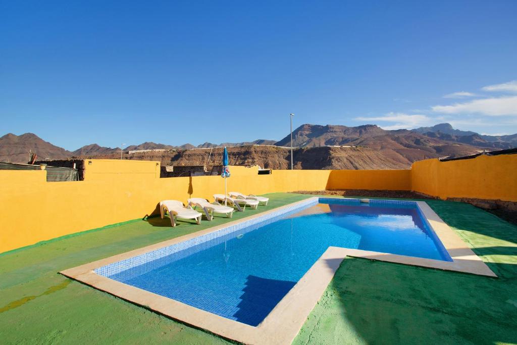 a swimming pool on the roof of a house with mountains at Villa Paraiso Aldeano 1+2 in La Aldea de San Nicolas