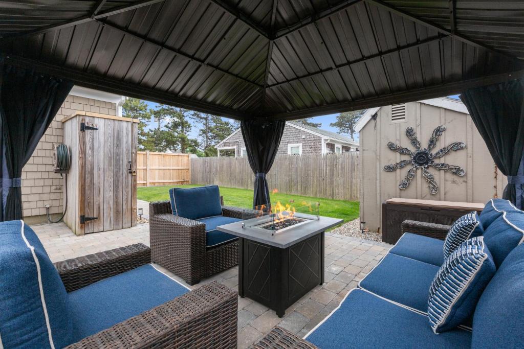 an outdoor patio with blue chairs and a fire pit at 3-min Walk To Beach! Private Luxury Backyard! in Dennis