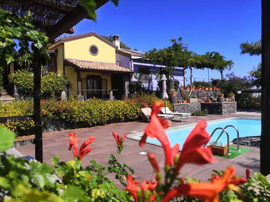 une maison et une piscine avec des fleurs rouges dans l'établissement Alberto's Mt.Etna B&B, à Zafferana Etnea