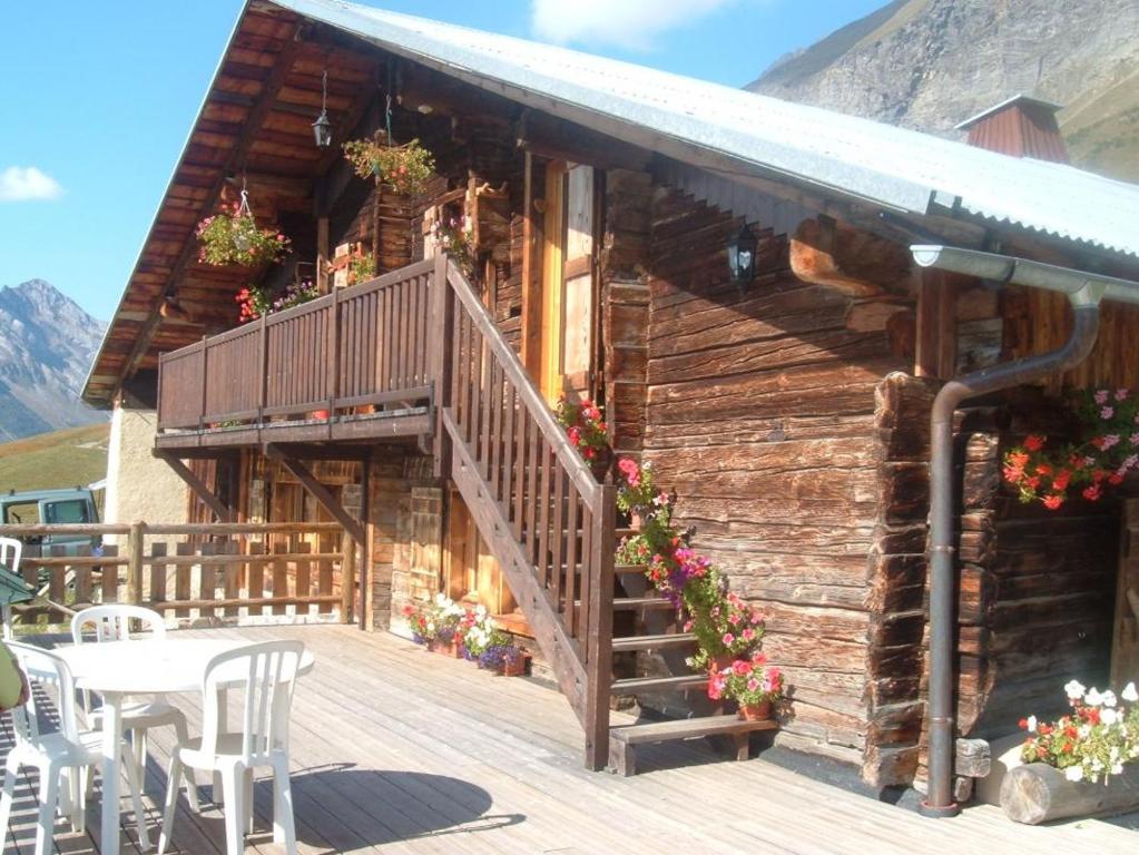 Ce chalet en bois dispose d'une terrasse avec une table et des chaises. dans l'établissement Le megevan-dans les alpages, à La Giettaz