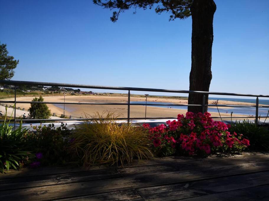a view of a beach with a tree and flowers at Maison/Appart de standing vue mer in Guidel