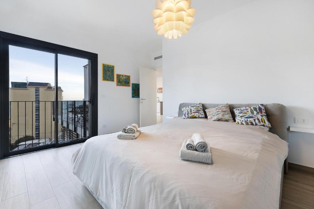 um quarto com uma grande cama branca e uma grande janela em Appartamento con vista Mare Noli em Noli