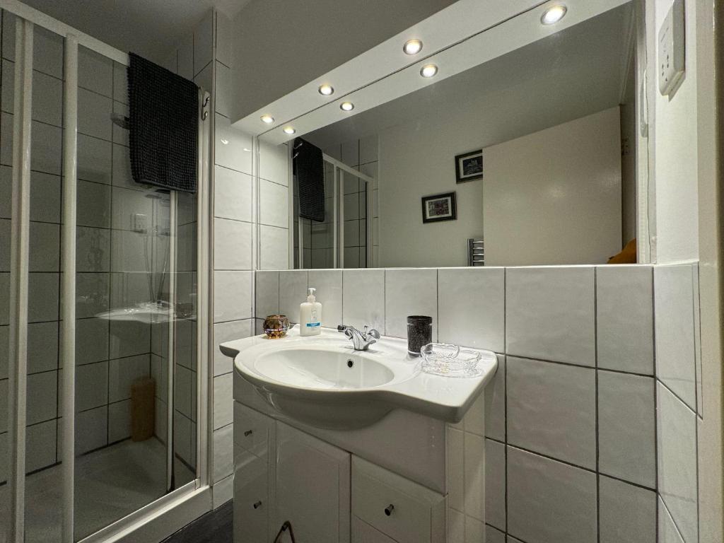 a bathroom with a sink and a shower and a mirror at Edinburgh TWO BEDROOM apartment with free side street parking 24 hours in Edinburgh