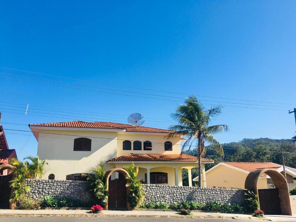 a house with a fence and a palm tree at Casa em Águas de Lindóia in Águas de Lindóia