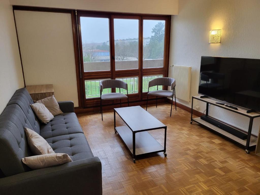 un salon avec un canapé et une télévision à écran plat dans l'établissement Chambre dans meublé tout équipé, à Angoulême