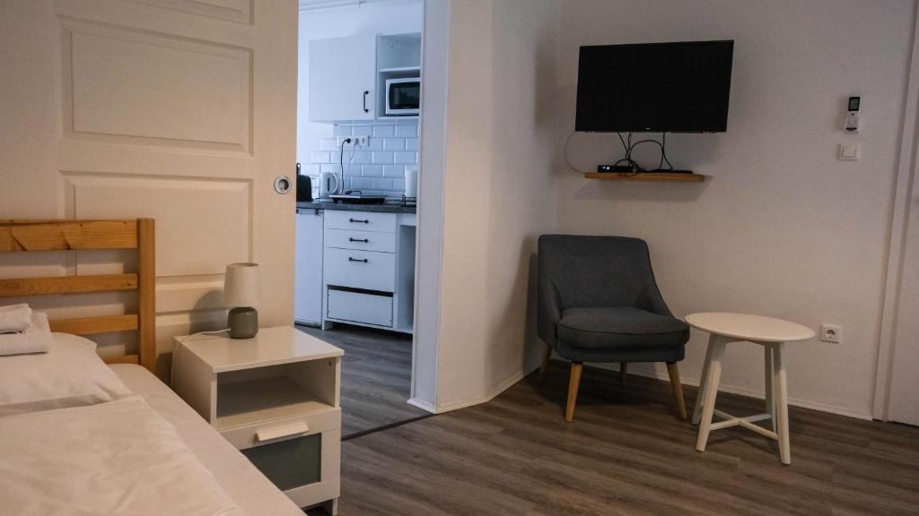 een slaapkamer met een bed en een stoel en een keuken bij Jókai 19 Vendégház in Veszprém