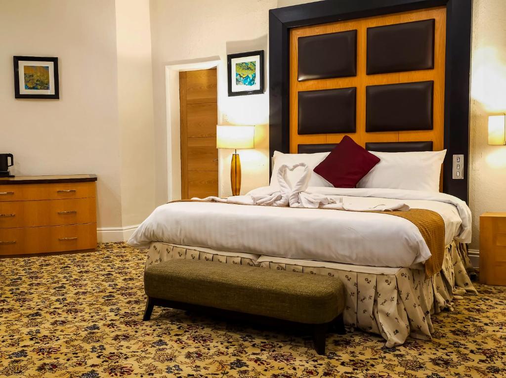 - une chambre avec un grand lit et un banc à côté dans l'établissement Crown Hotel Stone, à Stone